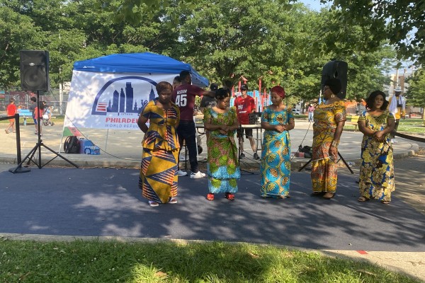 World Refugee Day Philadelphia 2021, image is of five women standing in a park wearing gowns made from colorful African dutch wax textiles