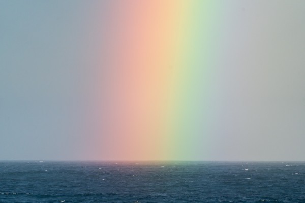 Blurred Rainbow in the sky over a sea Photo by Ben Mack