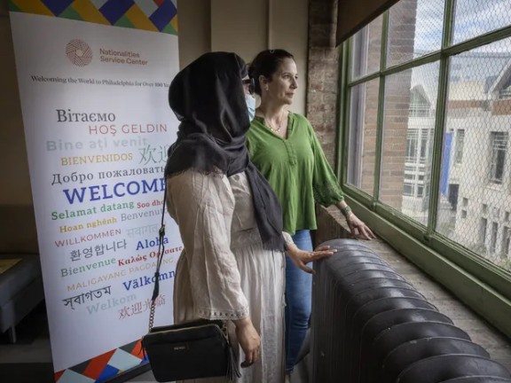 Two women stand at a window at NSC