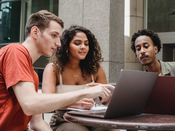 Colleagues look together at laptop Photo by William Fortunato