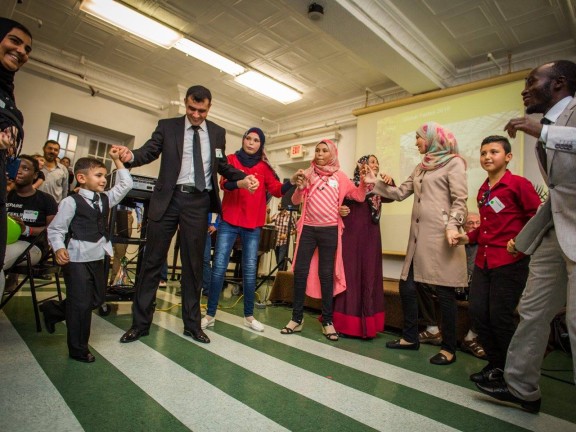 "NSC clients dancing the 'dabke,' a traditional Arab dance, at the annual NSC Thanksgiving Celebration." Taken by Ashley LaBonde of Wide Eyed Studios